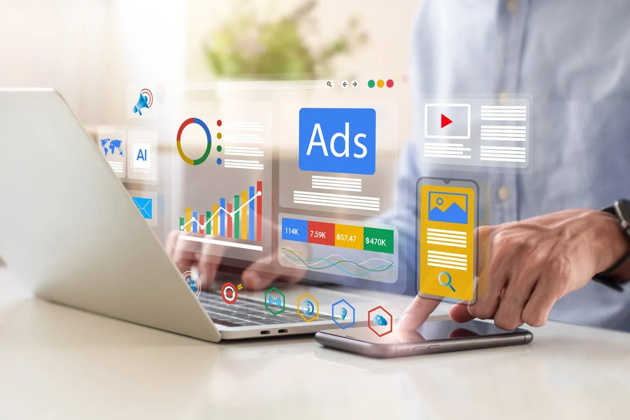 Google Ads per il B2B: grafici, metriche di campagna e interfaccia Ads sovrapposti a un laptop e uno smartphone su una scrivania
